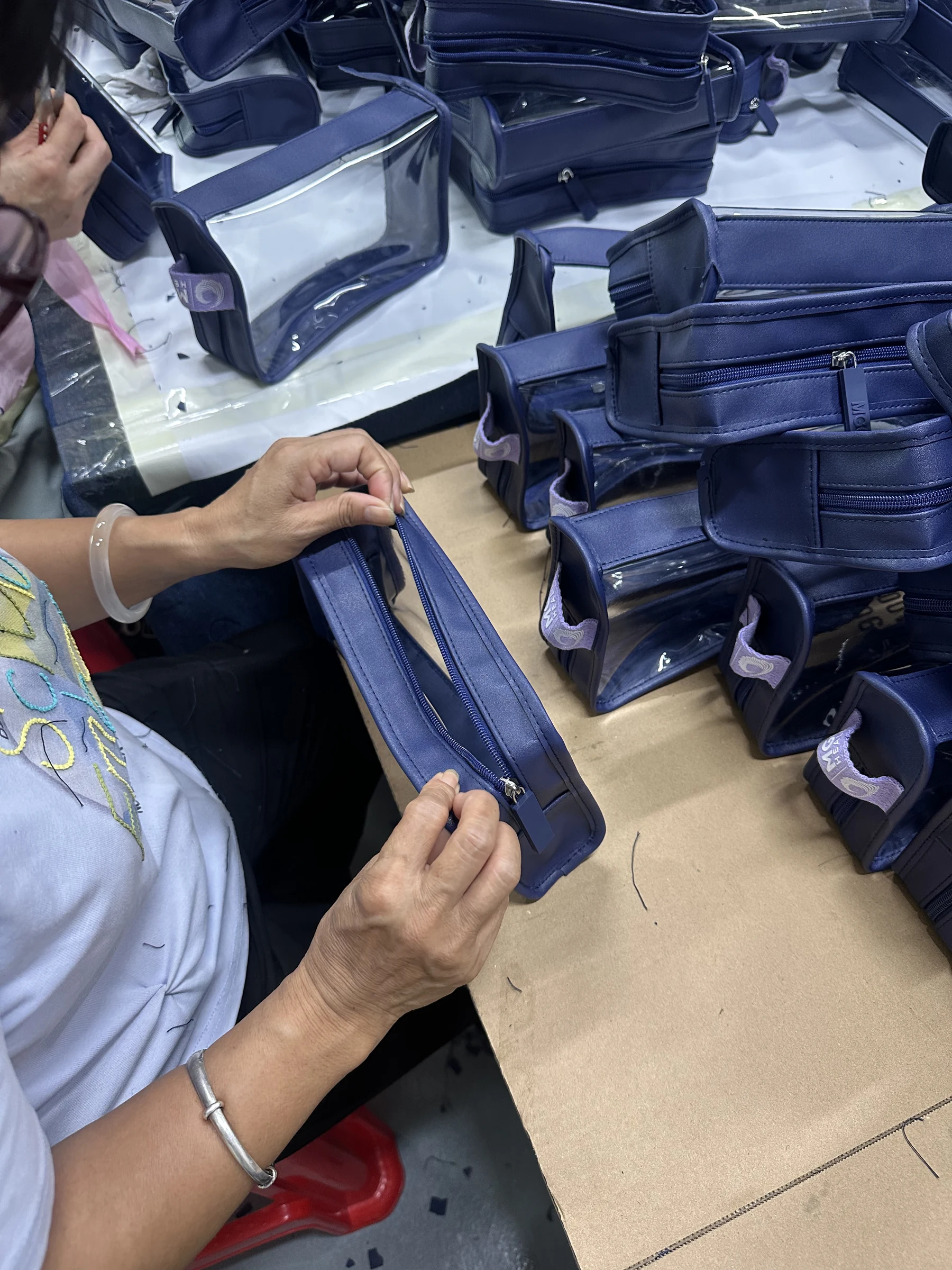 Real Hongzhao inspector checking zipper function and workmanship on finished custom cosmetic bags